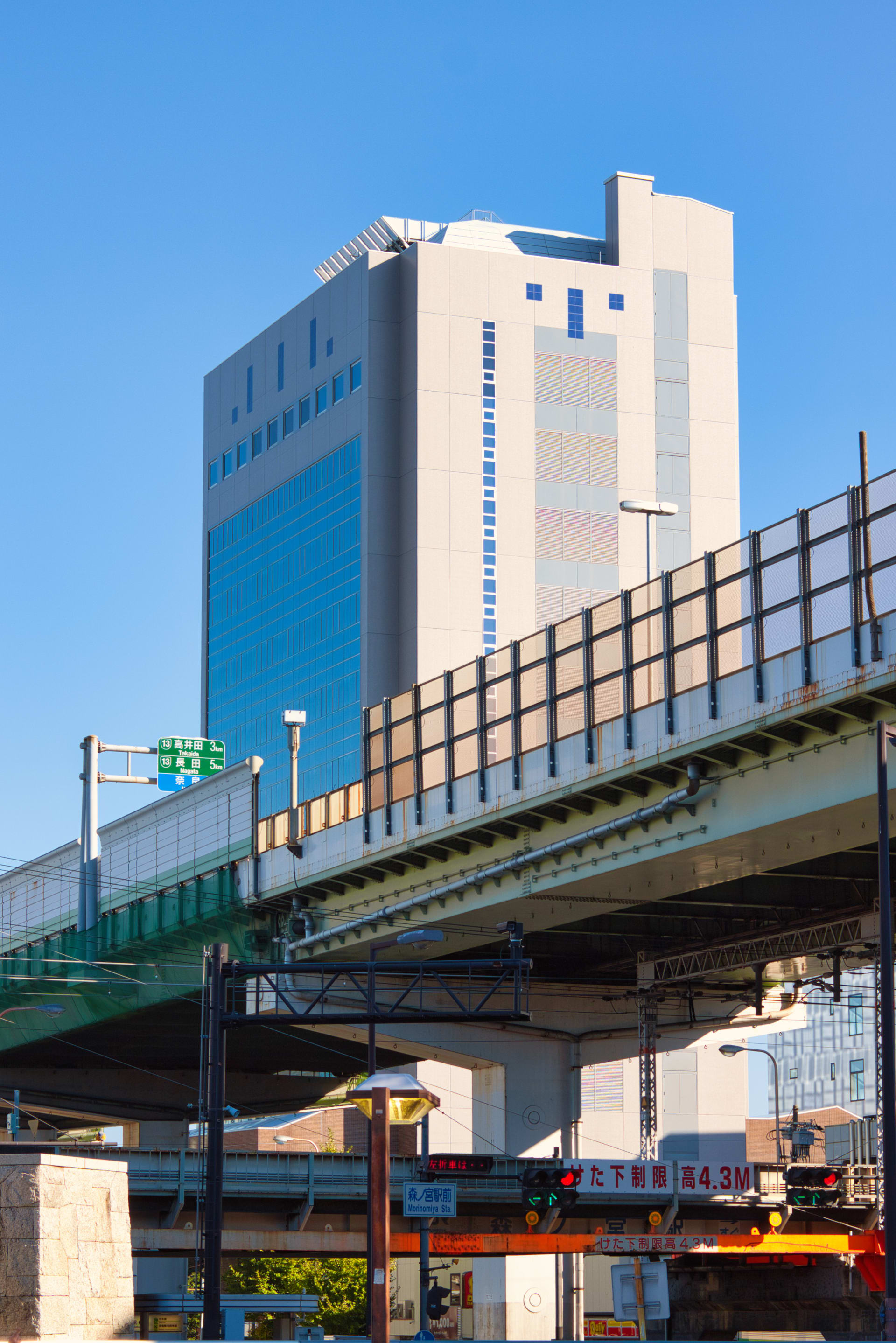 A building appears behind a highway overpass. I snapped this shot while heading back to Morinomiya Station from Osaka Castle Park.