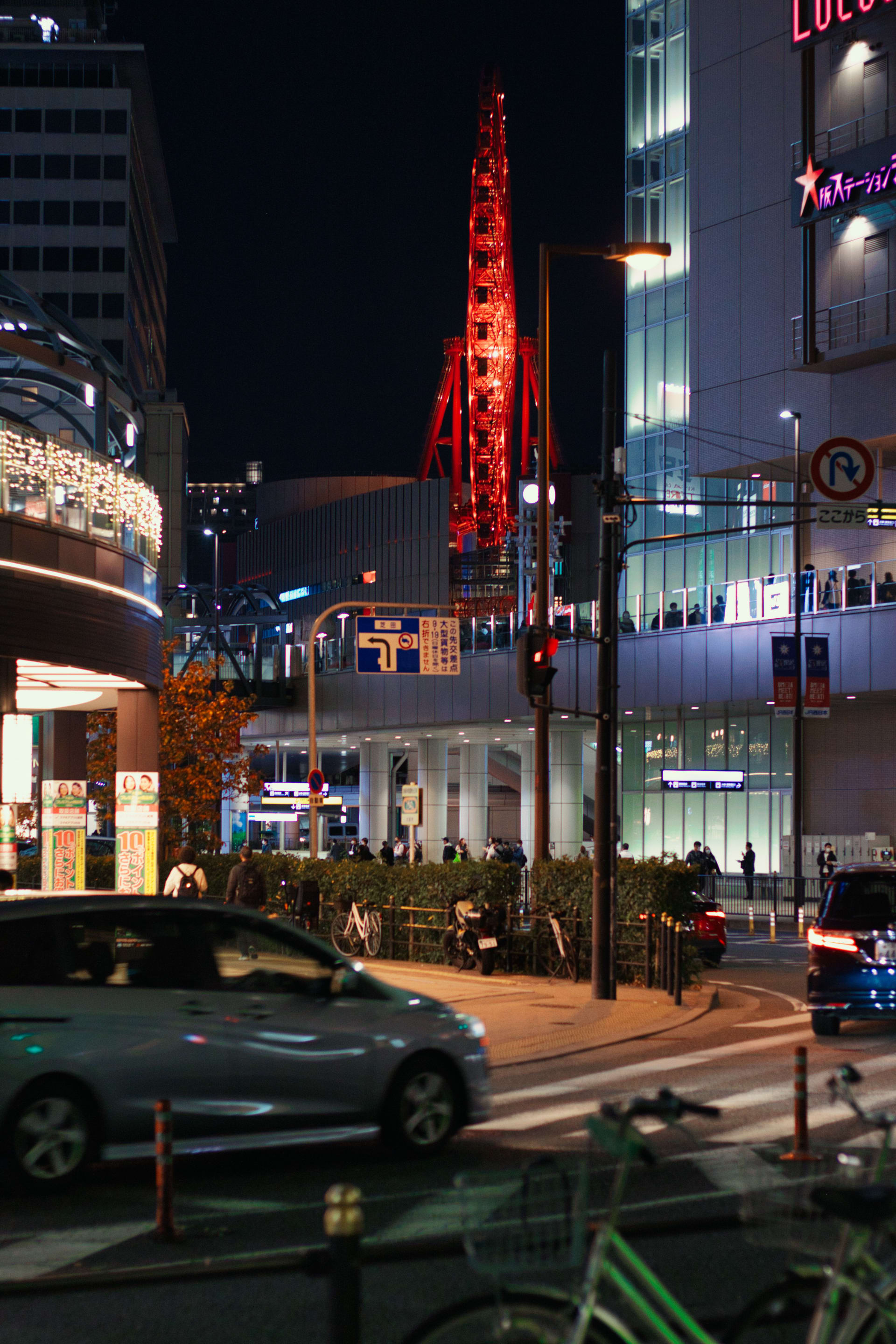 The Hep Five Ferris Wheel basked in red light as seen from street level in Osaka.